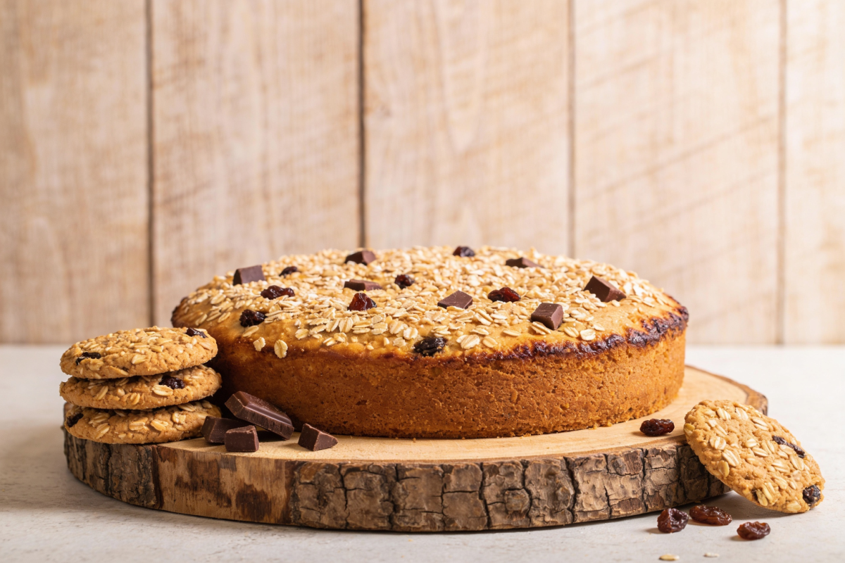 Biscoitos vitaminados de aveia com chocolate e uvas passa dourados em bandeja de madeira