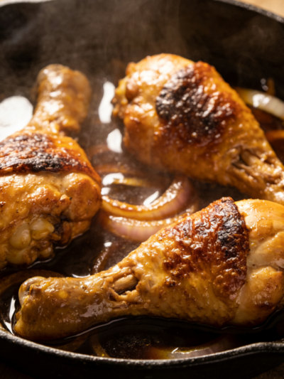 frango com cebola queimada em panela de ferro com caldo escuro e pedaços suculentos de coxa e sobrecoxa