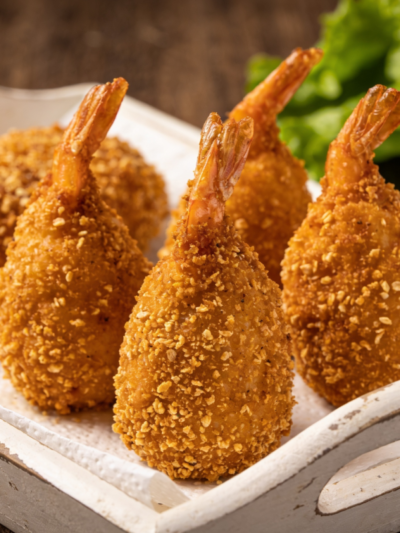 frango crocante dourado com casquinha empanada servido em travessa branca com folhas de alface e limão