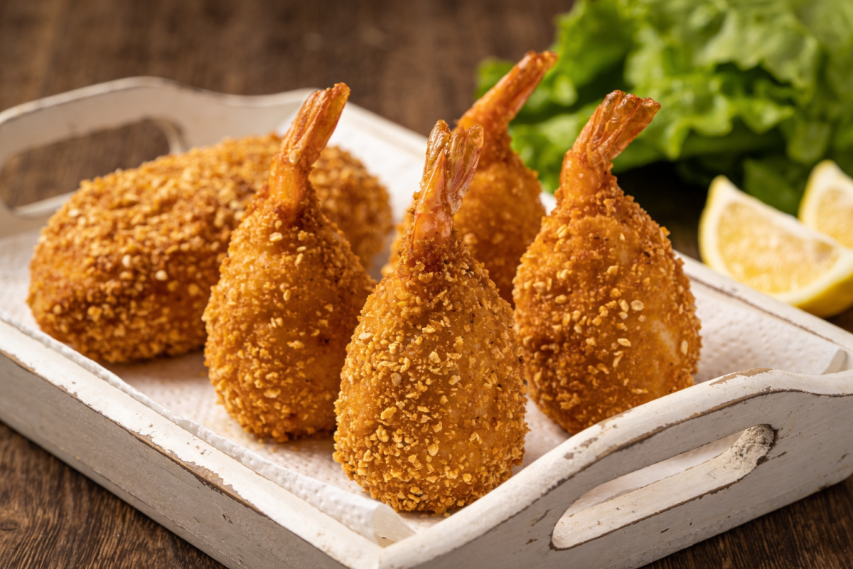 frango crocante dourado com casquinha empanada servido em travessa branca com folhas de alface e limão