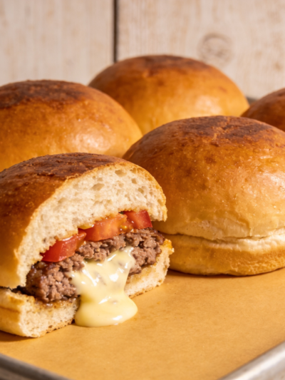 hamburguer assado no pão caseiro dourado cortado ao meio mostrando recheio suculento