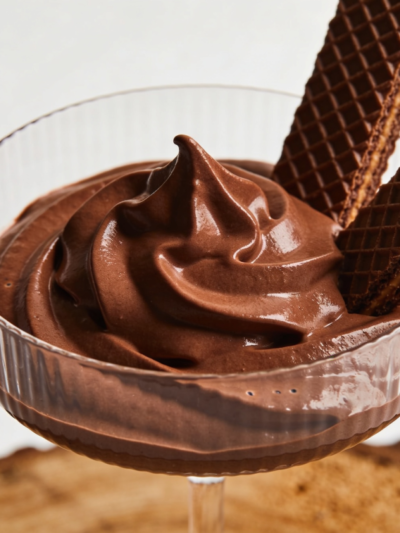 mousse quero mais cremoso servido em taça de vidro com pedaços de chocolate Bis decorando a superfície