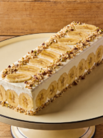pavê de banana cremoso em travessa de vidro com camadas de banana caramelizada, creme de baunilha e biscoito, polvilhado com canela