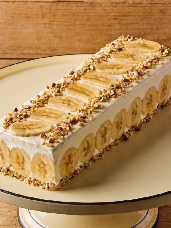 pavê de banana cremoso em travessa de vidro com camadas de banana caramelizada, creme de baunilha e biscoito, polvilhado com canela