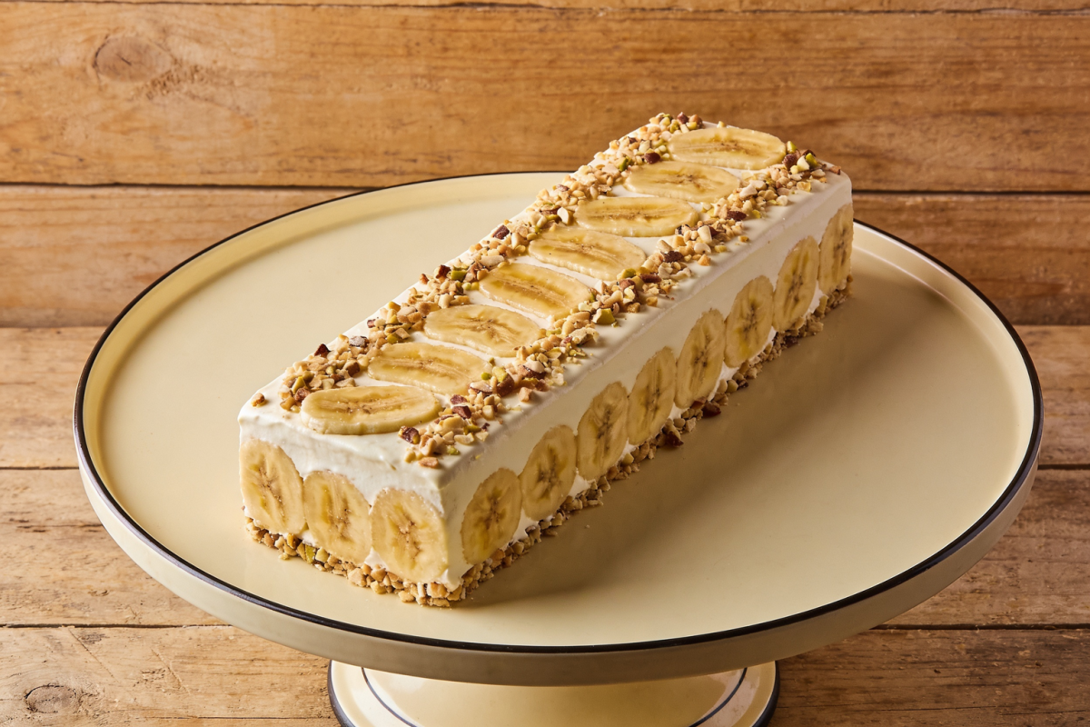pavê de banana cremoso em travessa de vidro com camadas de banana caramelizada, creme de baunilha e biscoito, polvilhado com canela