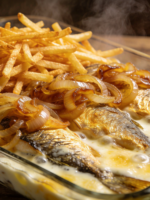 Peixe Surpresa suculento ao creme de mostarda com cebola dourada e batata palha crocante em travessa de vidro