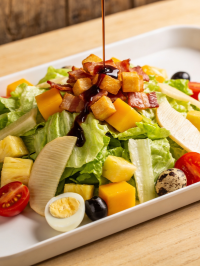 salada de verão da Dami com manga, abacaxi, atum, bacon crocante e molho balsâmico em travessa branca