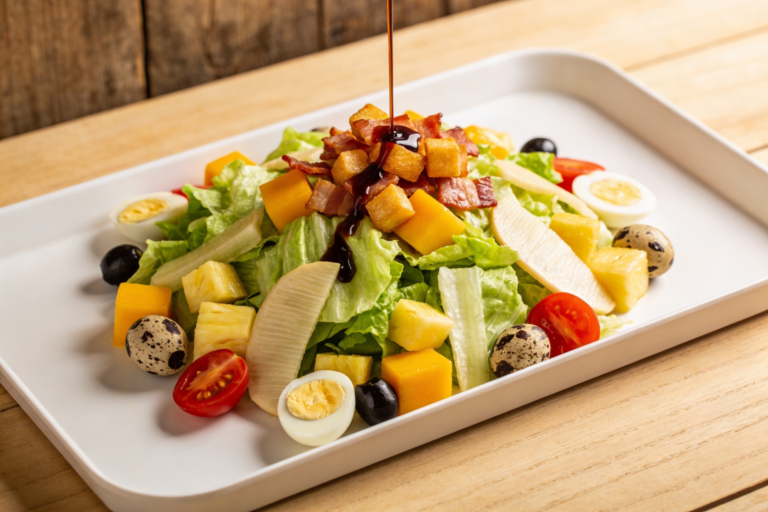 salada de verão da Dami com manga, abacaxi, atum, bacon crocante e molho balsâmico em travessa branca