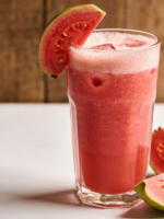 copo de suco de goiaba e iogurte cremoso cor-de-rosa com gelo e rodela de goiaba na borda
