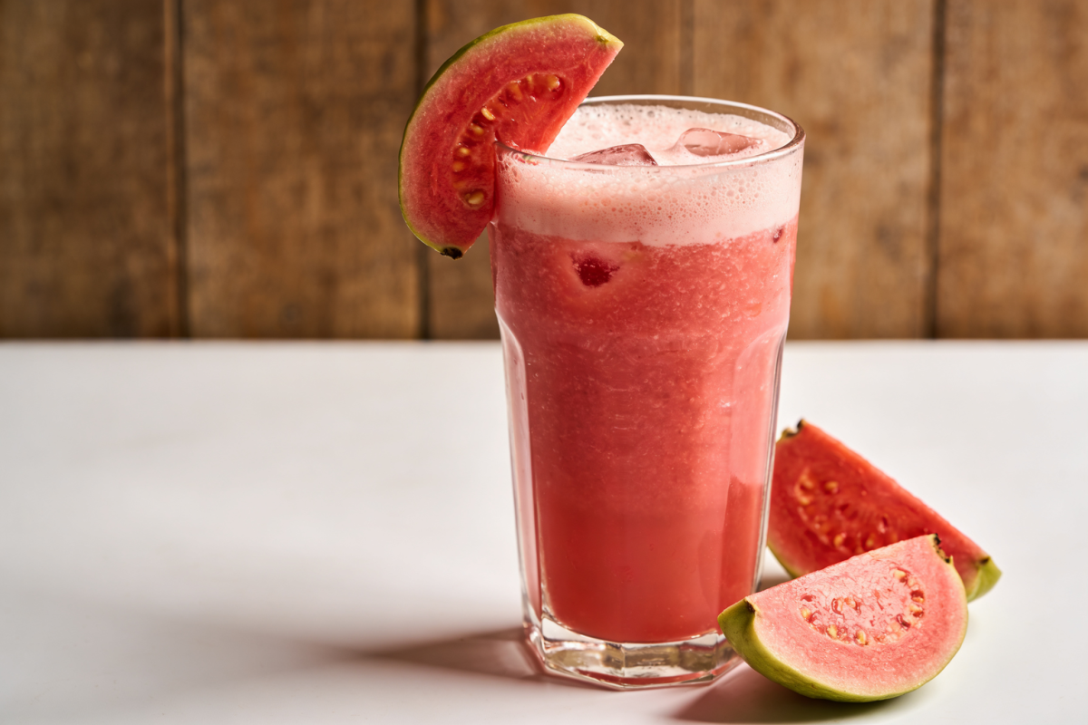 copo de suco de goiaba e iogurte cremoso cor-de-rosa com gelo e rodela de goiaba na borda