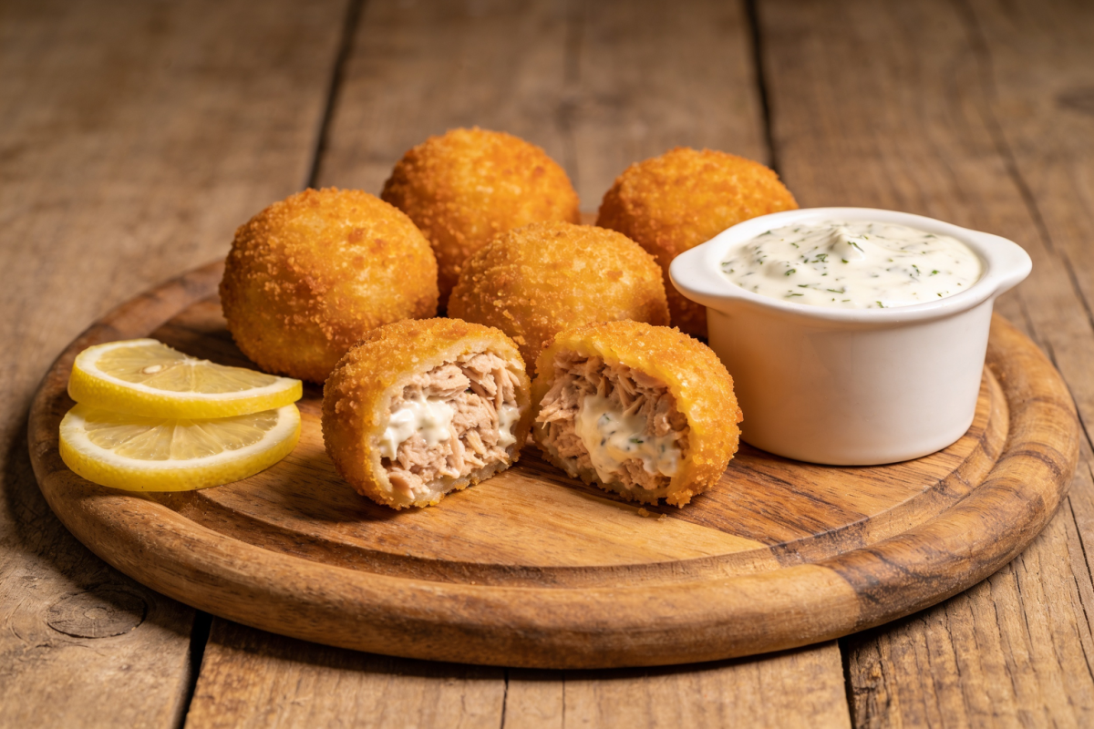 croquetes de atum dourados e crocantes servidos em bandeja com molho e limão