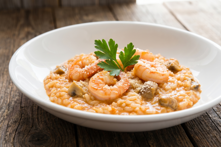 Risoto de camarão cremoso a minha moda com molho de tomate, champignon e queijo ralado em prato fundo branco